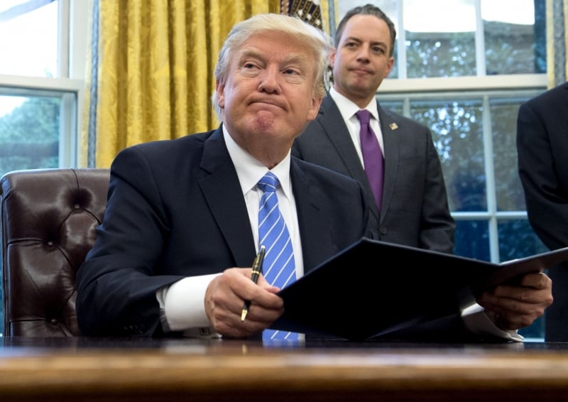 490452-01-02
US President Donald Trump signs an executive order as Chief of Staff Reince Priebus looks on in the Oval Office of the White House in Washington, DC, January 23, 2017.
Trump on Monday signed three orders on withdrawing the US from the Trans-Pacific Partnership trade deal, freezing the hiring of federal workers and hitting foreign NGOs that help with abortion. / AFP PHOTO / SAUL LOEB
      Caption