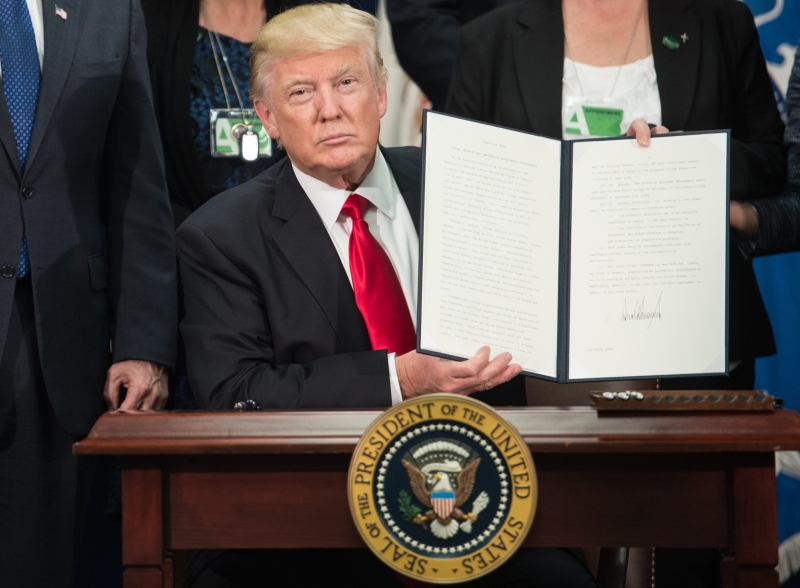 US President Donald Trump signs an executive order to start the Mexico border wall project at the Department of Homeland Security facility in Washington, DC, on January 25, 2017. / AFP PHOTO / NICHOLAS KAMM
      Caption