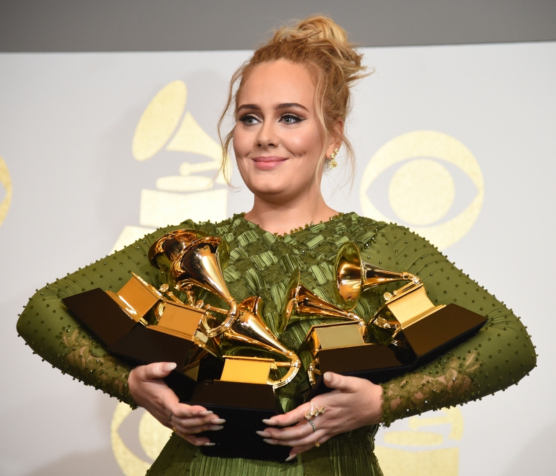 Adele poses in the press room with her trophies, including the top two Grammys of Album and Record of the Year for her blockbuster hit 