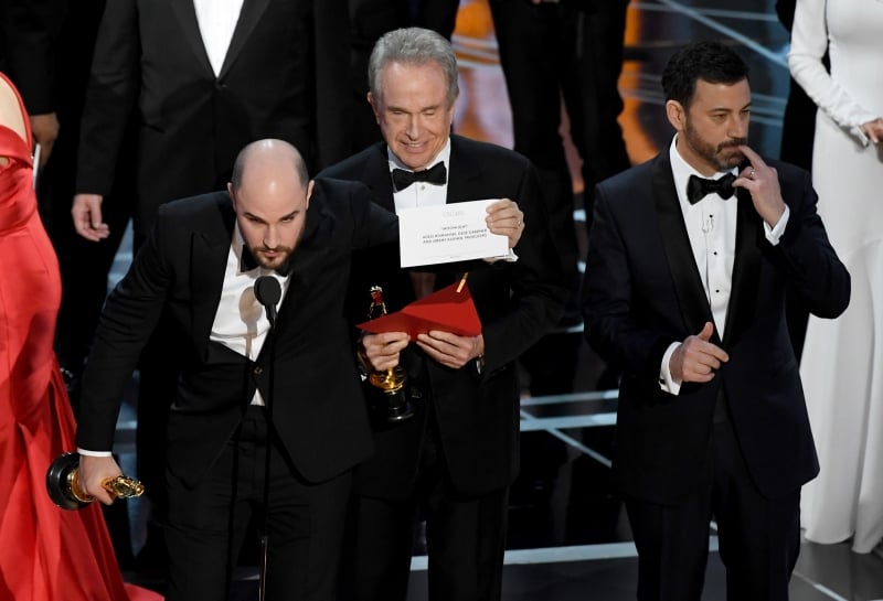 HOLLYWOOD, CA - FEBRUARY 26: 'La La Land' producer Jordan Horowitz (L) holds up the winner card reading actual Best Picture winner 'Moonlight' after a presentation error with actor Warren Beatty and host Jimmy Kimmel onstage during the 89th Annual Academy Awards at Hollywood & Highland Center on February 26, 2017 in Hollywood, California.   Kevin Winter/Getty Images/AFP
      Caption