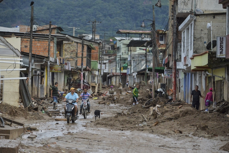 People look at the damage caused by mudslides following heavy rains in Mocoa, Putumayo department, southern Colombia on April 2, 2017. 
The death toll from a devastating landslide in the Colombian town of Mocoa stood at around 200 on Sunday as rescuers clawed through piles of muck and debris in search of survivors. / AFP PHOTO / LUIS ROBAYO
      Caption