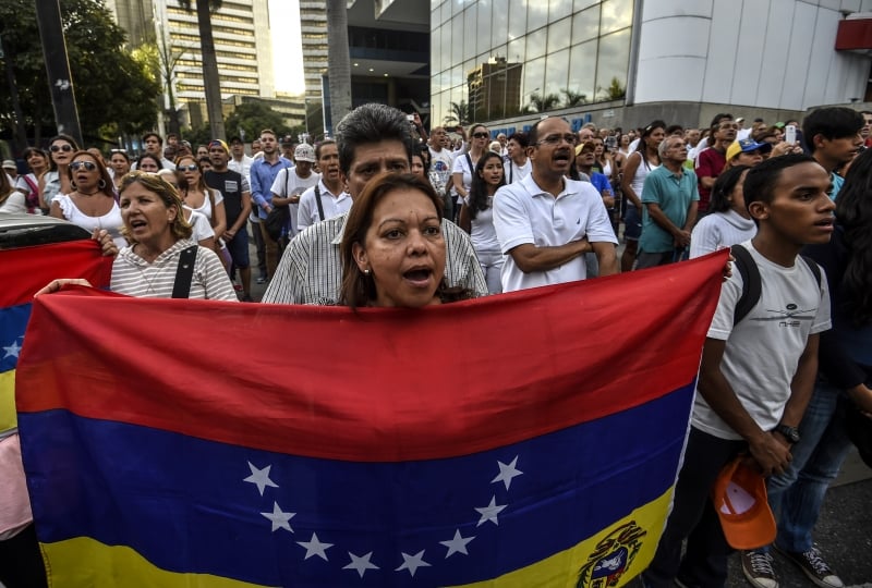 Venezuelan opposition activists march during a protest against President Nicolas Maduro's government, in Caracas on April 15, 2017.
Venezuelan authorities said Friday they had arrested two opposition youth leaders, the latest move in a crackdown against ongoing anti-government protests that have left five people dead. / AFP PHOTO / JUAN BARRETO
      Caption