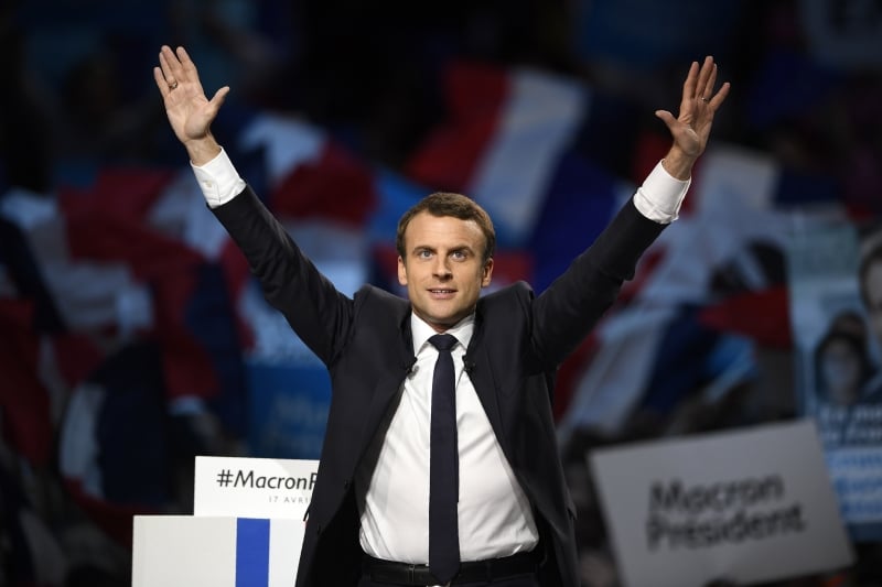 Presidential election candidate for the En Marche ! movement Emmanuel Macron raises his hands on stage as he delivers a speech during a campaign meeting on April 17, 2017 at the Bercy Arena in Paris. 
Macron planned his biggest rally yet at the Bercy sports and concert hall, a venue with a capacity of 20,000. The location near the economy ministry serves as a reminder that the relatively inexperienced Macron held the key economy portfolio for two years under his mentor Hollande.
 / AFP PHOTO / Eric FEFERBERG