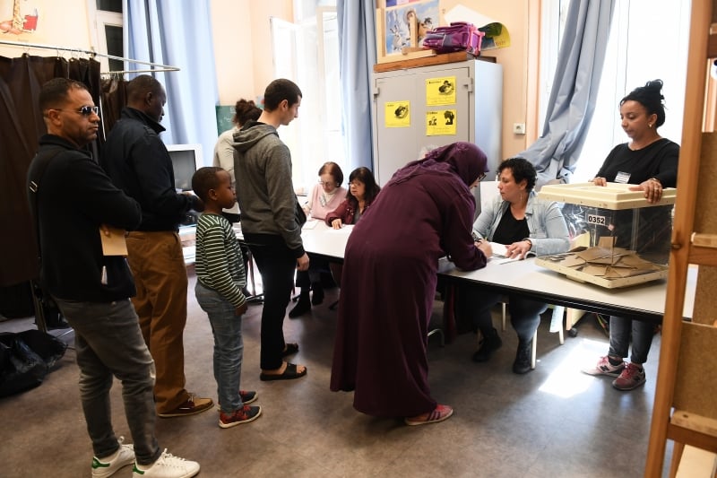 Voters queue at a polling station in Marseille, southern France, on April 23, 2017 during the first round of the French presidential election.  / AFP PHOTO / 
      Caption