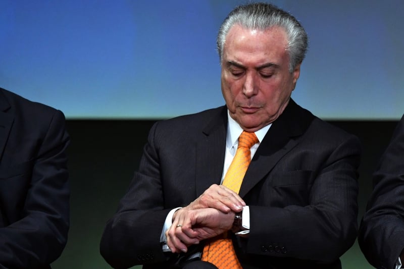 Brazilian President Michel Temer looks at his watch during an Investment Forum in Sao Paulo, Brazil on May 30, 2017. / AFP PHOTO / NELSON ALMEIDA
      Caption