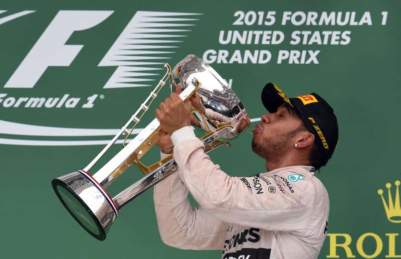 MERCEDES AMG PETRONAS BRITISH DRIVER LEWIS HAMILTON DRINKS CHAMPAGNE FROM HIS TROPHY ON THE PODIUM AFTER WINNING THE US FORMULA ONE GRAND PRIX AT THE CIRCUIT OF THE AMERICAS IN AUSTIN, TEXAS, ON OCTOBER 25, 2015. HAMILTON WON A THIRD FORMULA ONE WORLD TITLE ON SUNDAY WHEN HE SWEPT TO VICTORY IN THE UNITED STATES GRAND PRIX. AFP PHOTO/JEWEL SAMAD