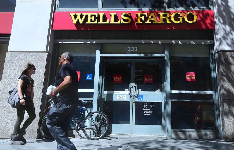 Pedestrians walk past a branch of Wells Fargo bank in downtown Los Angeles on October 3, 2016 in California. 
Wells Fargo, the second largest US bank by market value, has been accused of illegal conduct which saw employees boost sales figures by opening unauthorized deposit and credit accounts and then covertly fund them with customers' money.  / AFP PHOTO / FREDERIC J BROWN