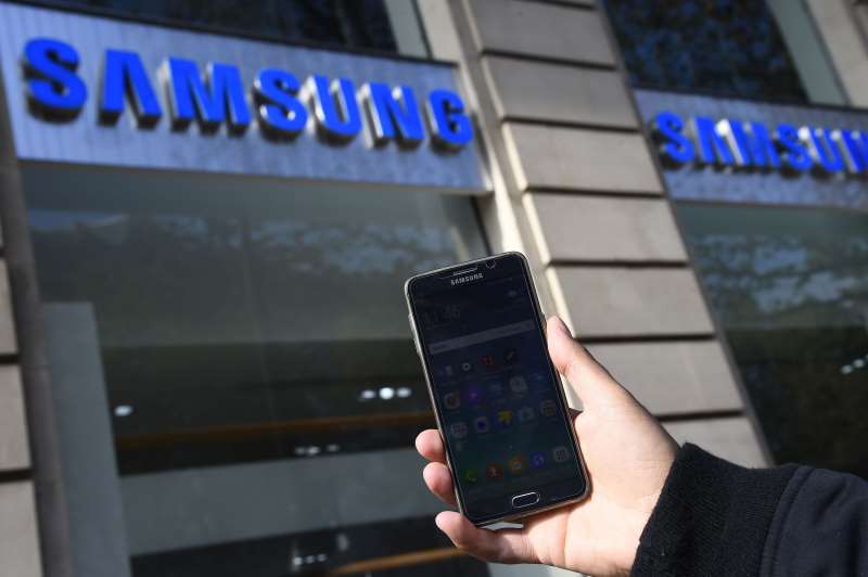 A person holds up a Samsung smart phone in front of the Samsung store in Paris on October 11, 2016. 
Samsung on October 11 pulled the final plug on its troubled Galaxy Note 7 smartphone, permanently discontinuing production of the flagship device that has been mired in a disastrous recall over exploding batteries. / AFP PHOTO / BERTRAND GUAY